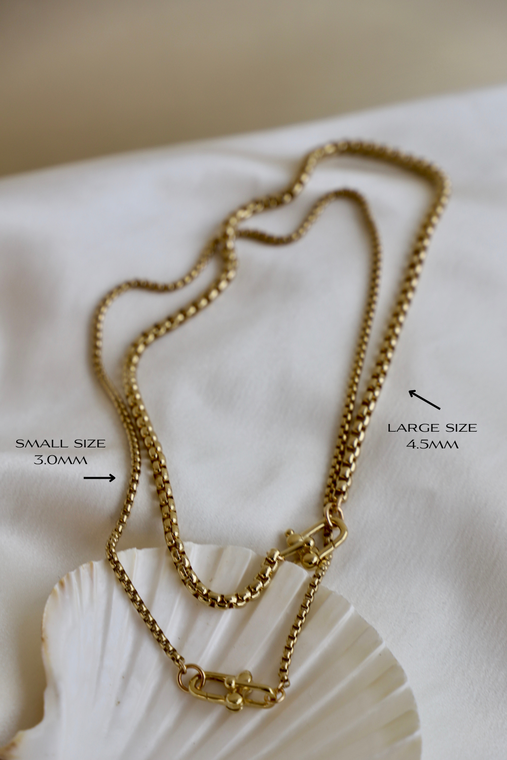 Gold chain necklace on a white shell with size labels