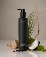 Black bottle of Homecourt coconut body wash with natural elements on a neutral background