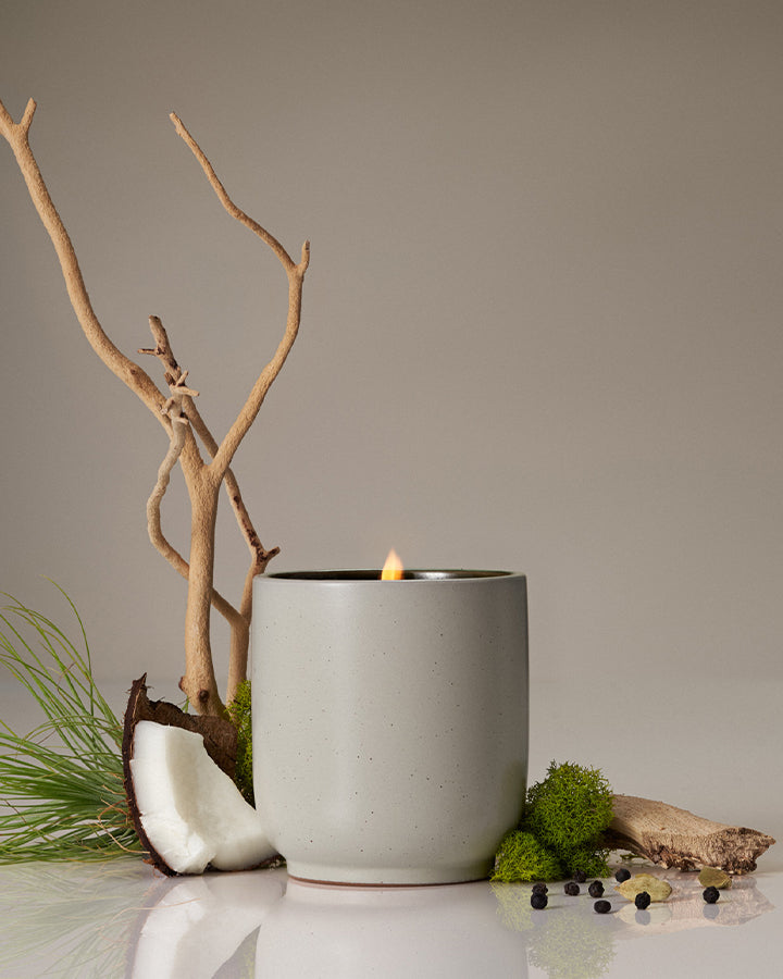 Candle in a concrete holder with natural elements on a neutral background
