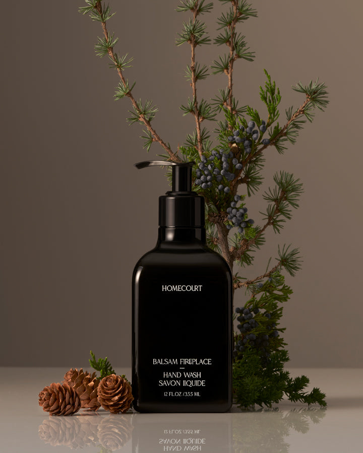 Black hand wash bottle labeled 'Homecourt' with decorative branches and pinecones on a neutral background