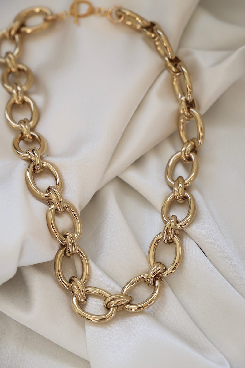 Gold chain necklace on a white fabric background