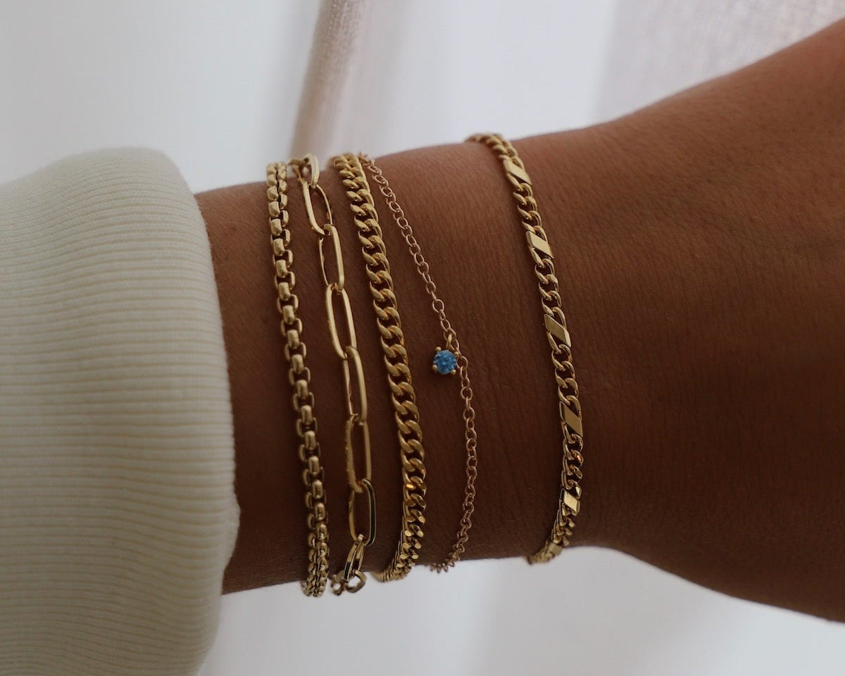 Gold chain bracelets on a wrist with a white background