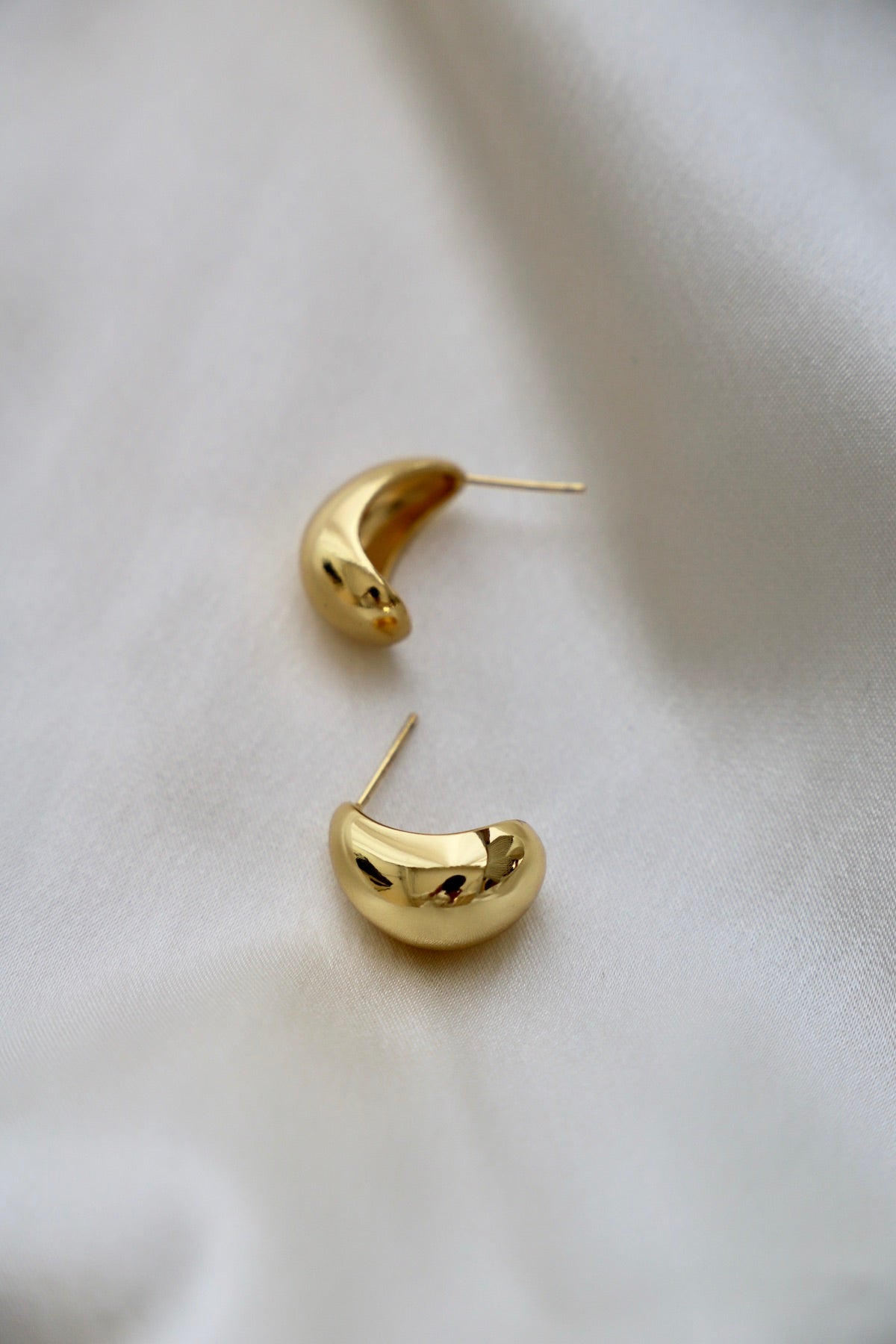 Gold hoop earrings on a light fabric background
