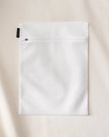 Homecourt white zipper laundry bag on a beige background