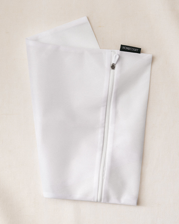 White zippered laundry pouch with a brand label 'Homecourt' on a beige background