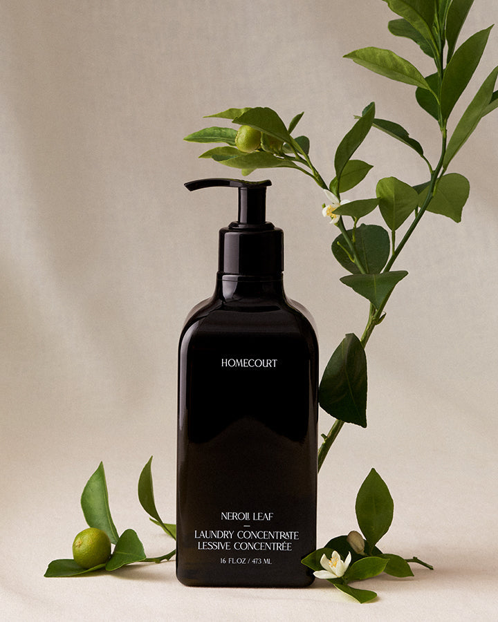 Black bottle of Homecourt laundry concentrate with green leaves on a beige background