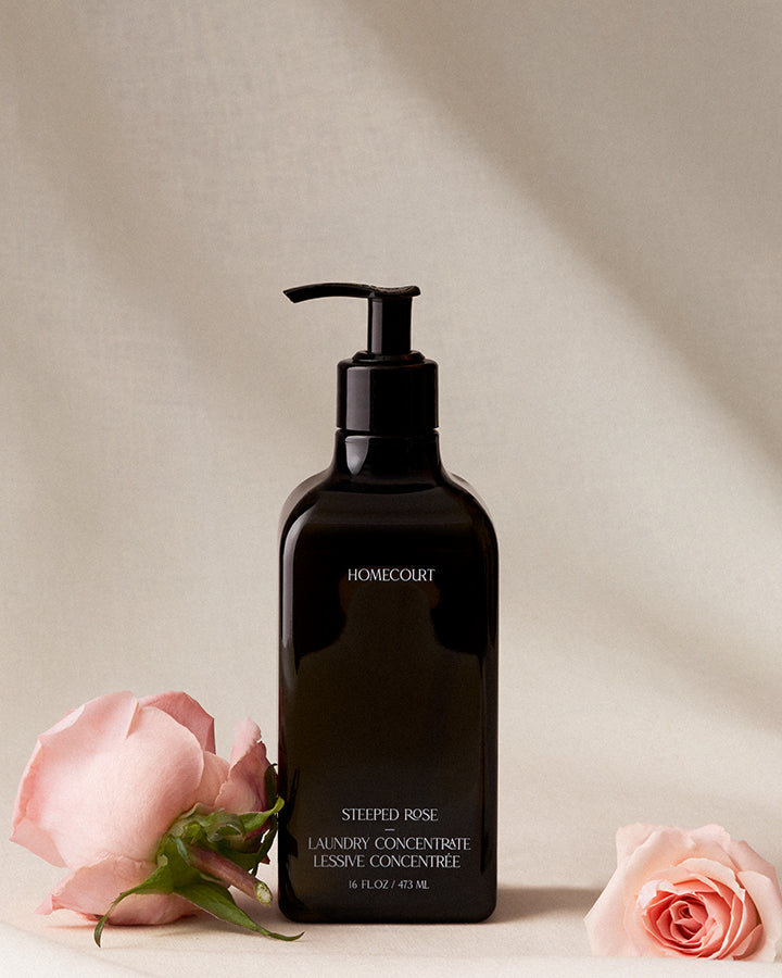 Black bottle of Homecourt laundry concentrate with pink roses on a beige background
