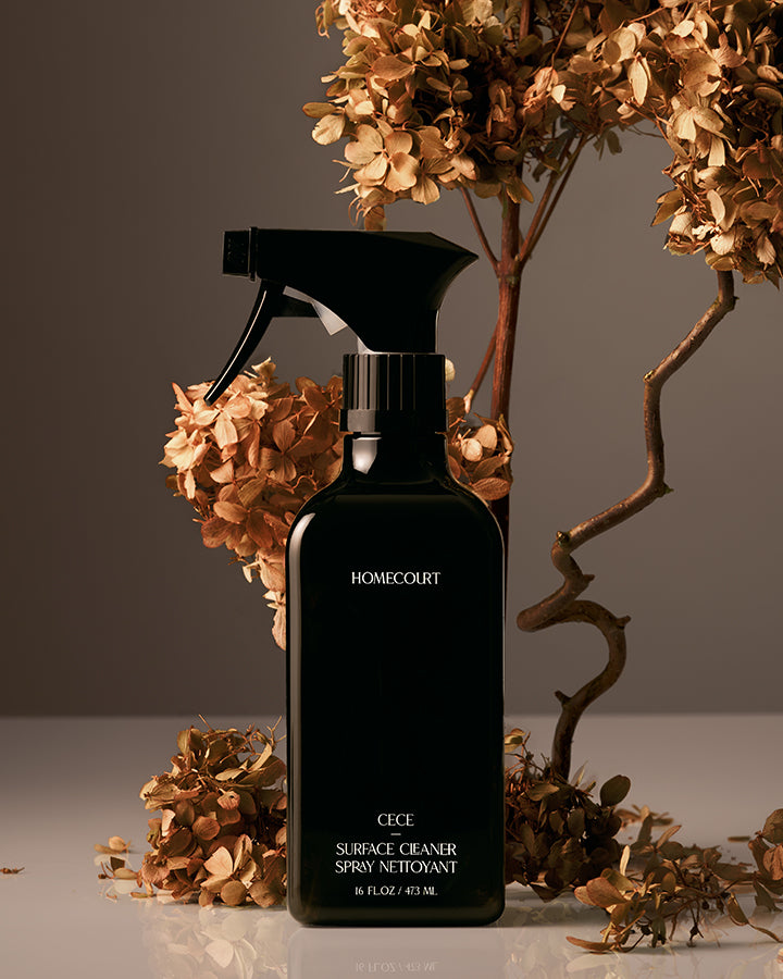 Black spray bottle labeled 'Homecourt' with dried flowers in the background