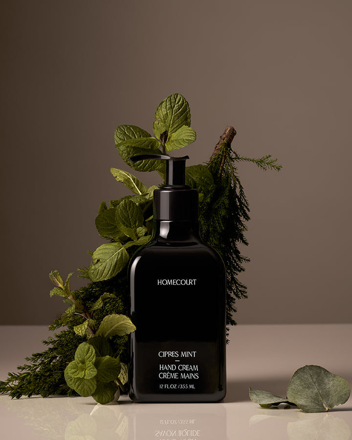 Black hand cream bottle labeled 'Homecourt' with green leaves on a neutral background