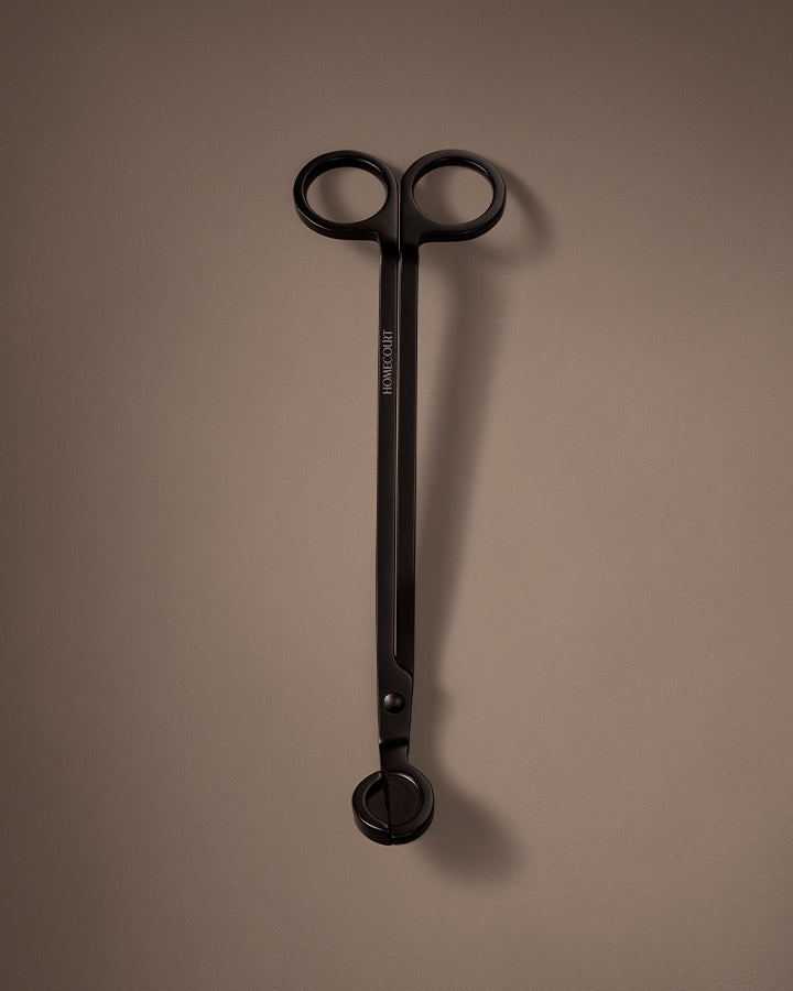 Black candle wick trimmer on a brown background