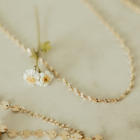 Gold necklaces on a light background with small flowers.