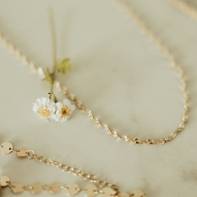 Gold necklaces on a light background with small flowers.