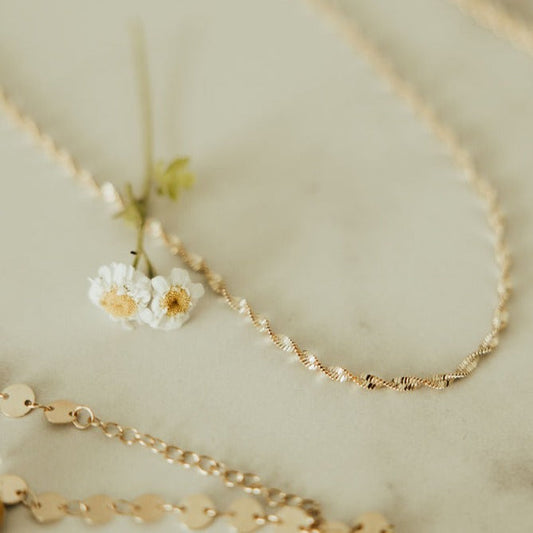 Gold necklaces on a light background with small flowers.