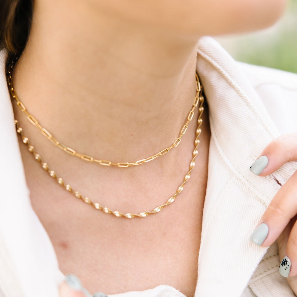 Gold chain necklace on a person's neck with a blurred background