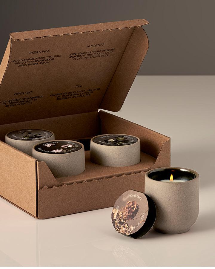 Set of three concrete candles with a cardboard box on a neutral background