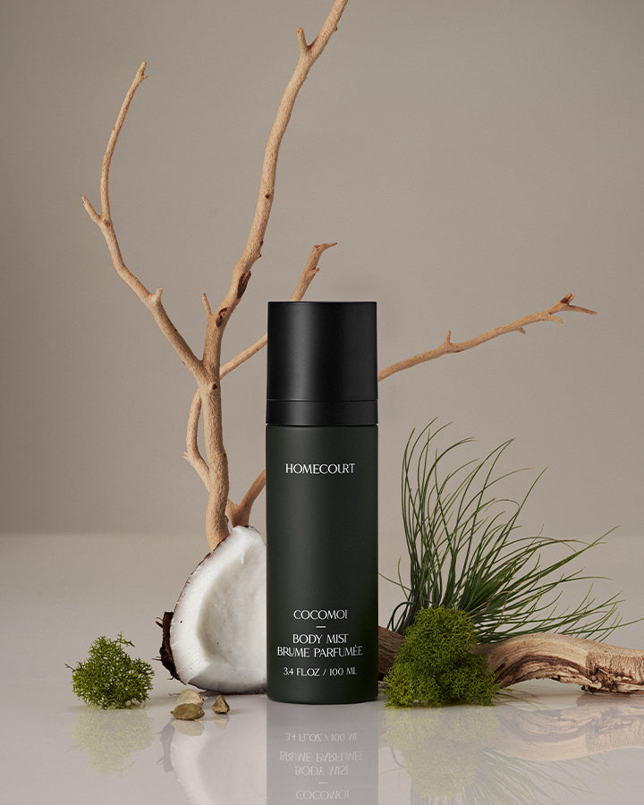 Black body mist bottle labeled 'Homecourt' on a neutral background with natural elements.