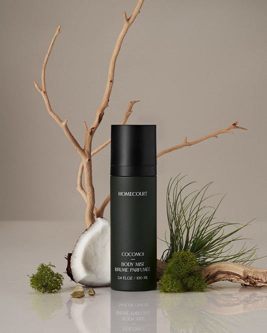 Black body mist bottle labeled 'Homecourt' on a neutral background with natural elements.