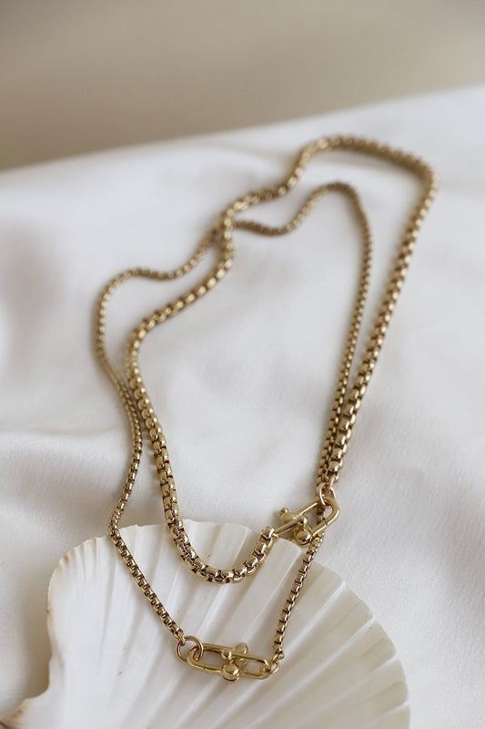 Gold chain necklace on a white shell with a neutral background