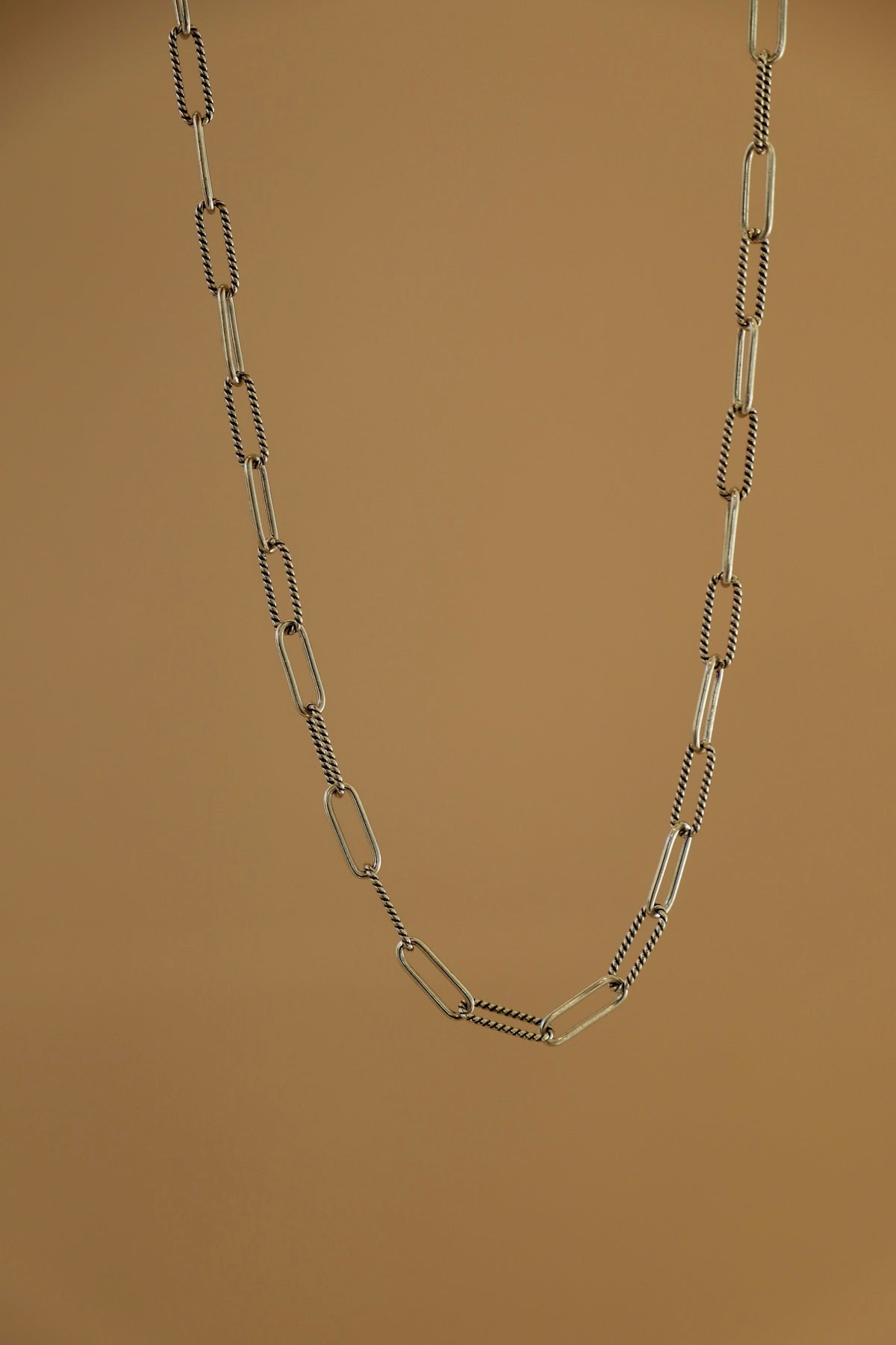 Silver chain necklace on a brown background