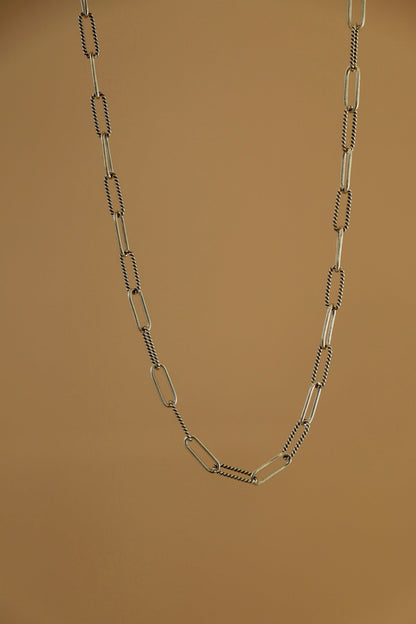 Silver chain necklace on a brown background
