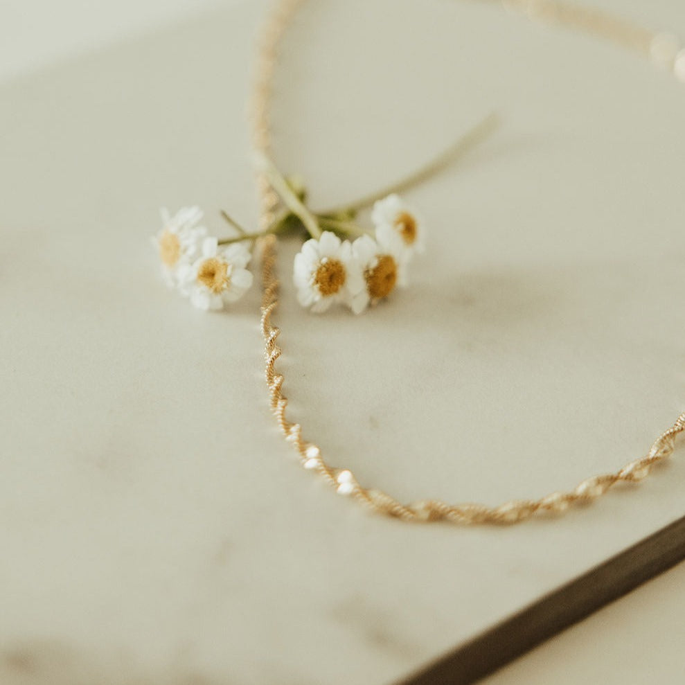 Gold necklace with small white flowers on a light background