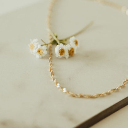 Gold necklace with small white flowers on a light background
