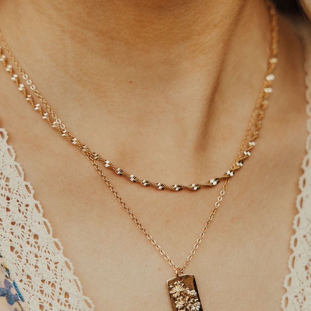 Gold necklace with a pendant on a person wearing a lace garment.