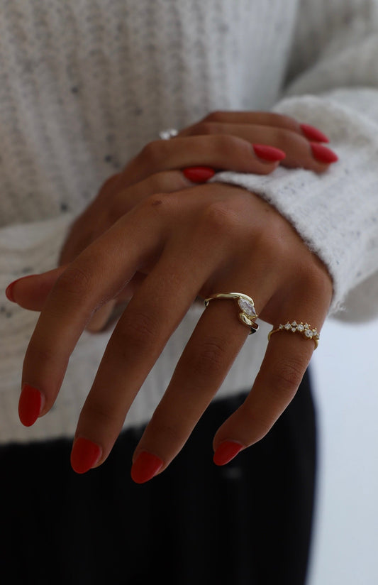 Close-up of a person's hand with red nail polish wearing two gold rings.