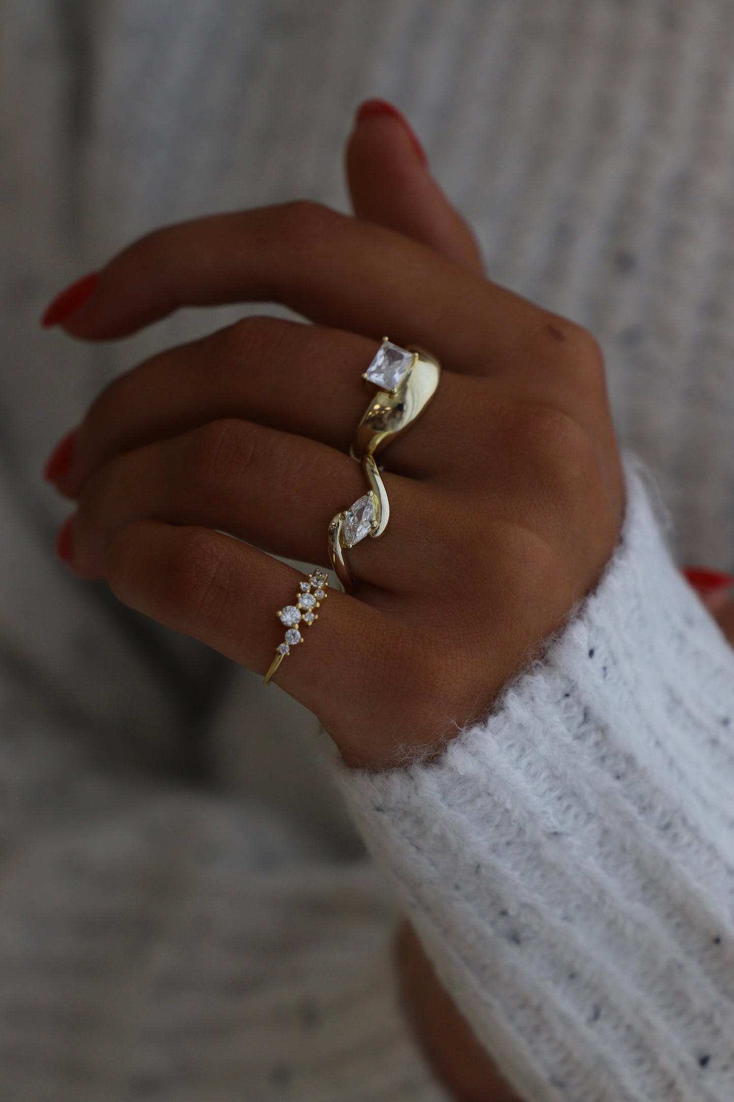 Hand wearing a gold rings with diamonds on a blurred background