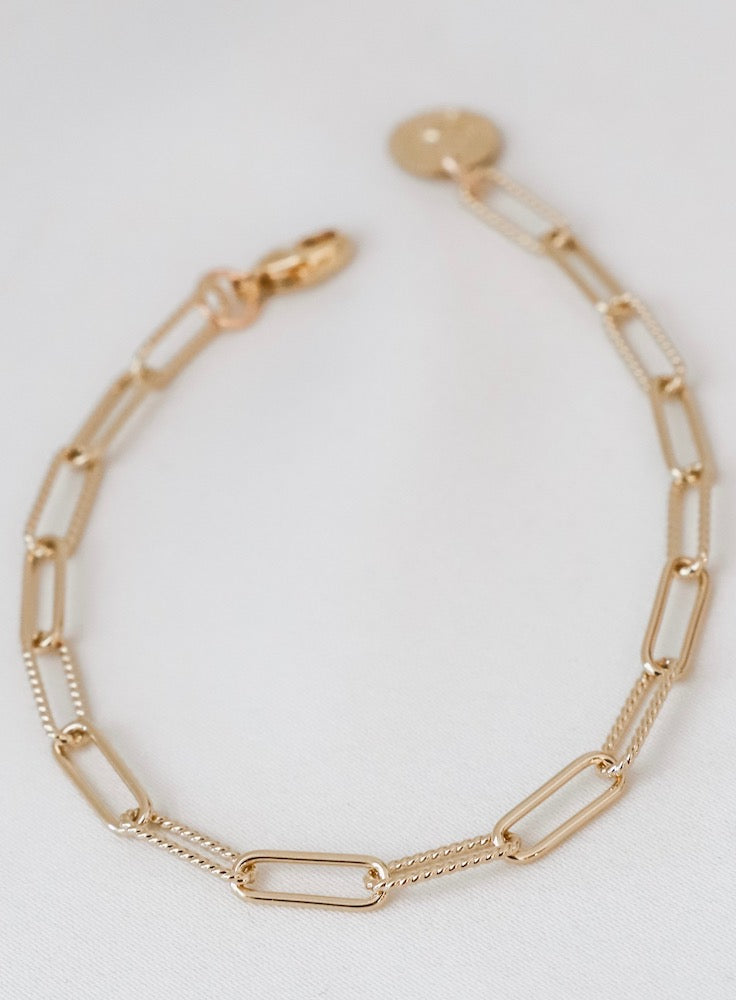 Gold chain bracelet on a light gray background