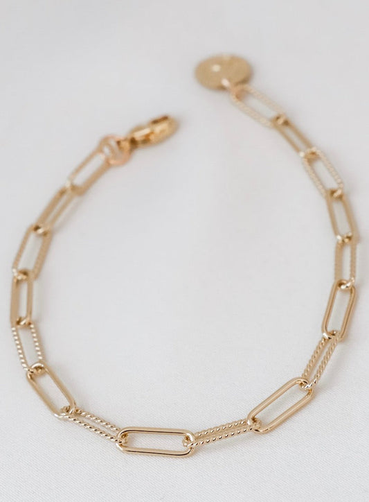 Gold chain bracelet on a light gray background