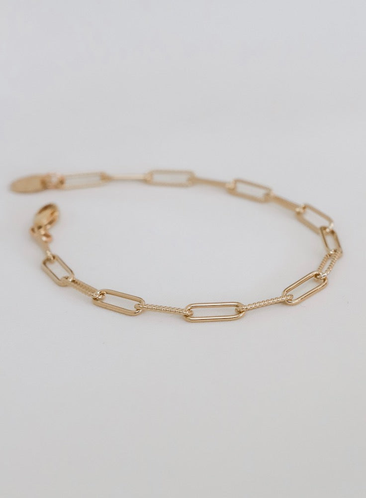 Gold chain bracelet on a light gray background