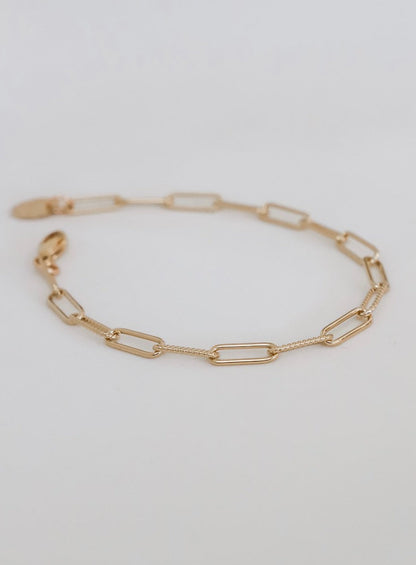 Gold chain bracelet on a light gray background