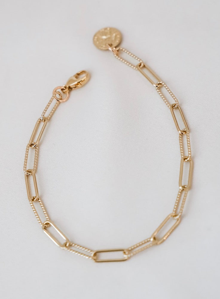 Gold chain bracelet on a light gray background