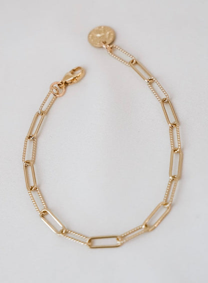 Gold chain bracelet on a light gray background