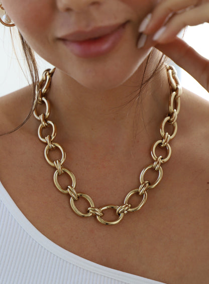 Gold chain necklace worn by a person with a blurred background