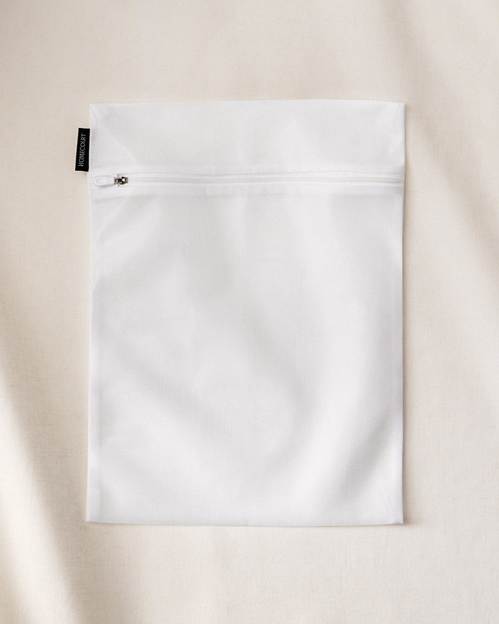 Homecourt white zipper laundry bag on a beige background