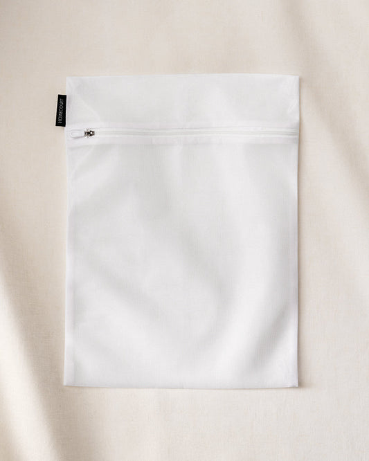 Homecourt white zipper laundry bag on a beige background