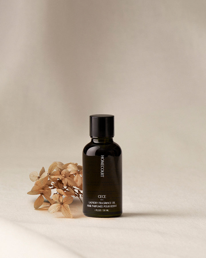 Black bottle of Homecourt oil with dried flowers on a beige background