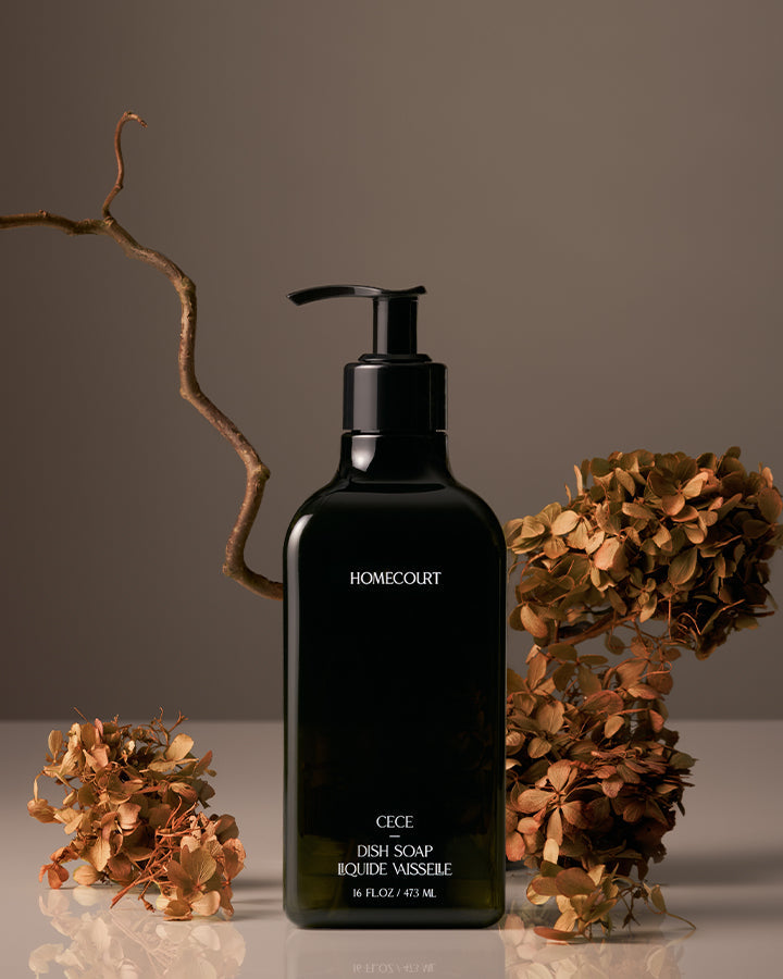 Black bottle of Homecourt dish soap with dried flowers on a neutral background