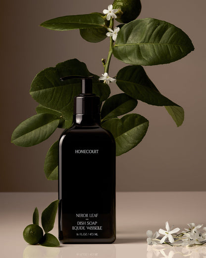 Black soap bottle labeled 'Homecourt' with green leaves and white flowers on a neutral background