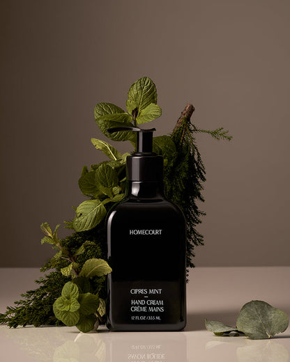 Black hand cream bottle labeled 'Homecourt' with green leaves on a neutral background