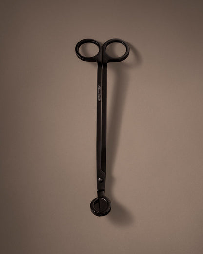 Black candle wick trimmer on a brown background