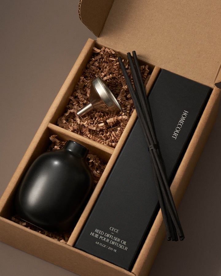 Gift diffuser set with black bottle, black box, and black reeds in a brown box.