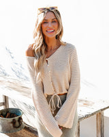 Woman wearing a beige crochet cardigan with a neutral background