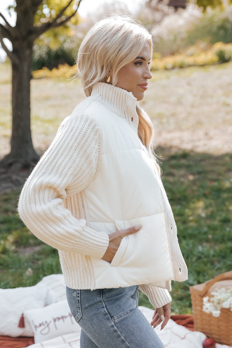 Woman wearing a cream-colored knit jacket outdoors with blurred background