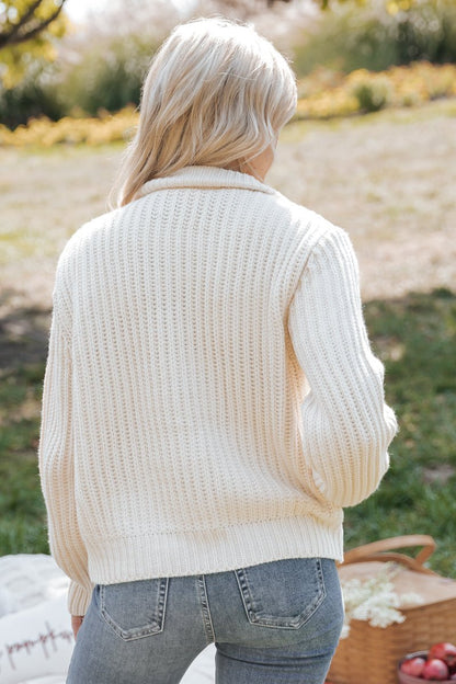 Person wearing a cream knitted cardigan jacket in an outdoor setting