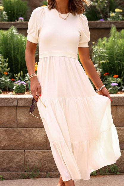 Woman wearing a white dress standing in front of a garden.